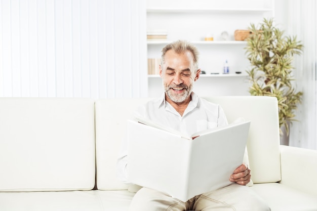 Homme d'affaires avec un magazine assis sur un canapé au bureau lumineux