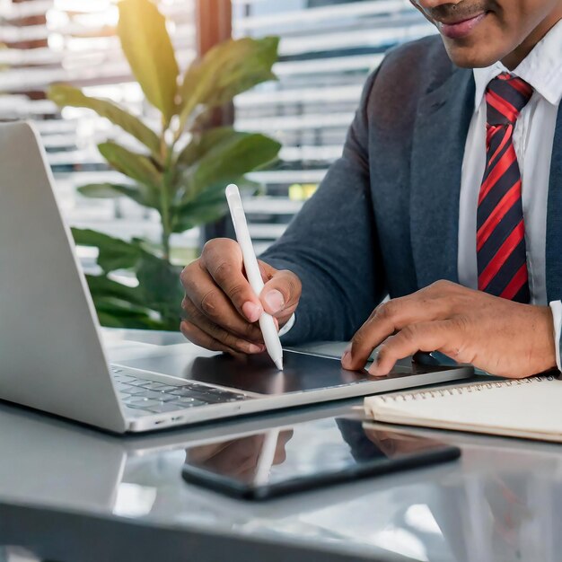 Homme d'affaires à la main avec un stylet signant sur une tablette numérique et travaillant sur un ordinateur portable