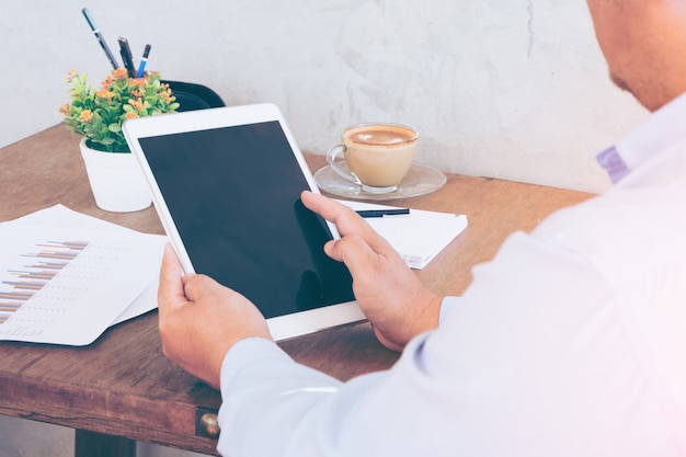 homme d&#39;affaires les mains sur une table avec tablette et tasse de café dans un bureau