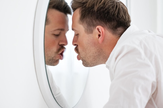 Homme d'affaires malheureux s'appuyant sur un miroir essayant de se calmer