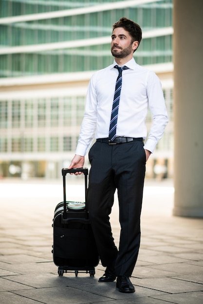 Photo homme d'affaires marchant avec un chariot de voyage d'affaires