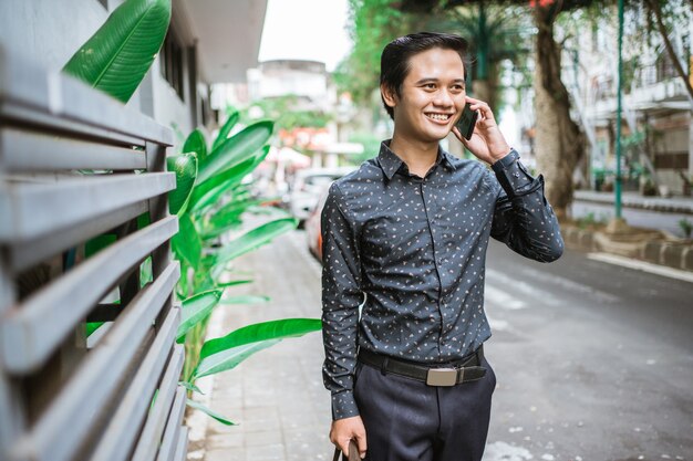 Homme d'affaires marchant sur un trottoir souriant allant au bureau avec un téléphone