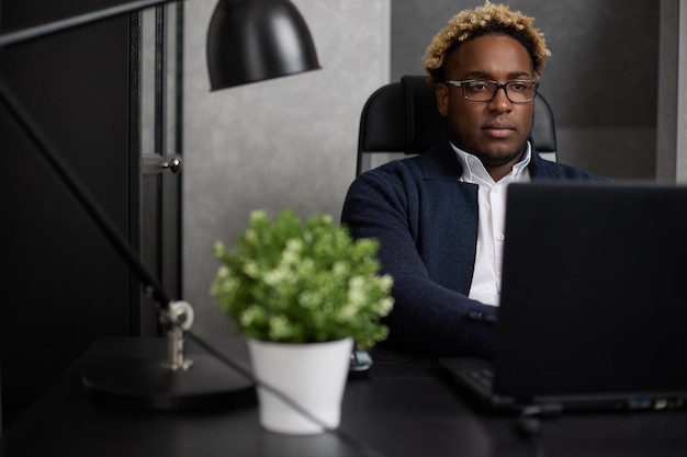 Homme d'affaires mature confiant travaillant sur un ordinateur portable noir dans un bureau moderne