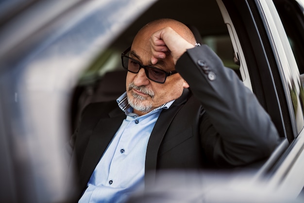 Homme d'affaires mature fatigué est assis à l'intérieur de sa voiture et pense à son travail.
