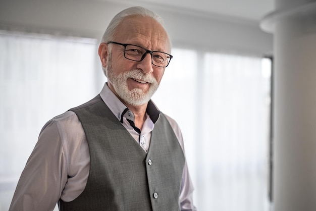 Homme d'affaires mature intelligent avec des lunettes souriant et regardant la caméra