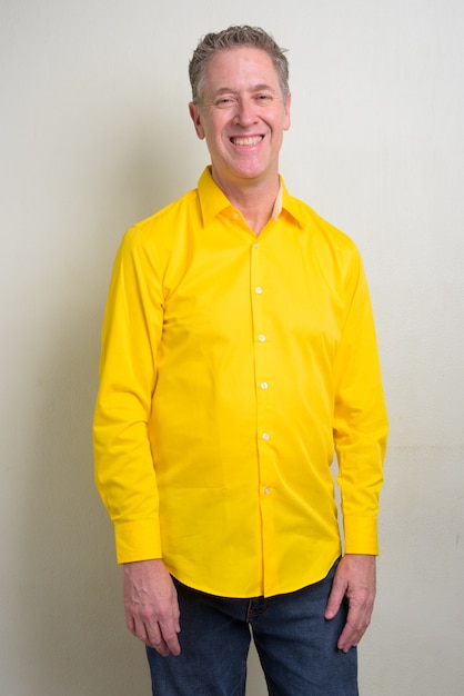 homme d'affaires mature portant une chemise jaune sur blanc