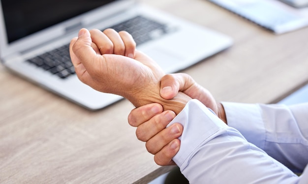 Homme d'affaires avec une mauvaise douleur au poignet dans la main après une blessure et une douleur au bureau Gros plan d'un homme d'affaires avec une tension douloureuse blessante et douloureuse assis à son bureau