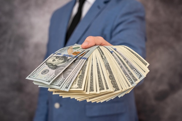 Un homme d'affaires met de l'argent en billets de banque en dollars dans la poche de son costume coûteux exquis Concept d'entreprise et de profit