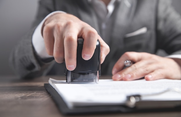 L'homme d'affaires met un cachet sur les documents au bureau.