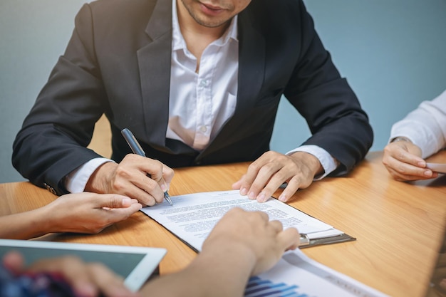 Homme d'affaires met la signature sous contrat lors d'une réunion de travail et passe de l'argent après des négociations