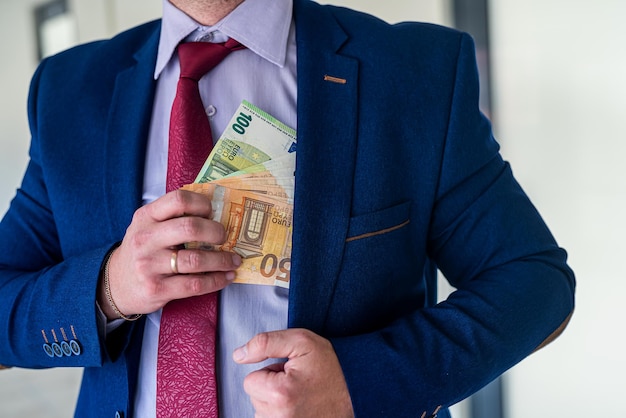 Homme d'affaires mettant de l'argent en euros dans son salaire de poche ou concept de corruption de pot-de-vin