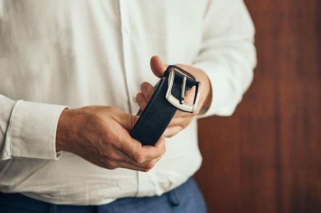 Homme d'affaires mettant un concept de mode et de vêtements de ceinturegroom se prépare le matin avant la cérémonie