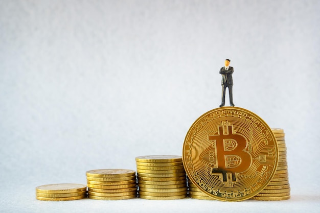 Homme d'affaires miniature debout Bitcoin étape de piles de pièces sur fond blanc et concept d'investissement en crypto-monnaie Trading sur l'échange de crypto-monnaie