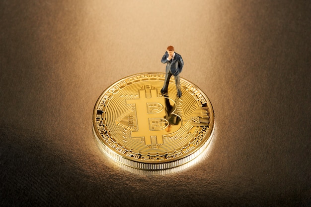 Homme d'affaires miniature debout sur un Bitcoin