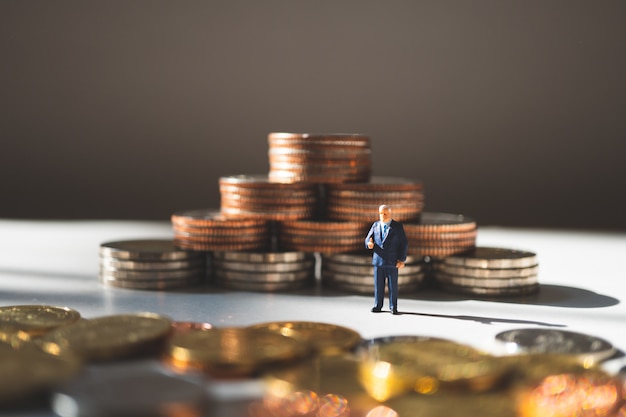 Homme d&#39;affaires miniature, debout sur des pièces de pile, utilisant comme concept commercial et financier