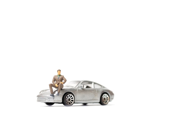 Homme d'affaires miniatures assis sur une voiture et copiez l'espace pour le texte