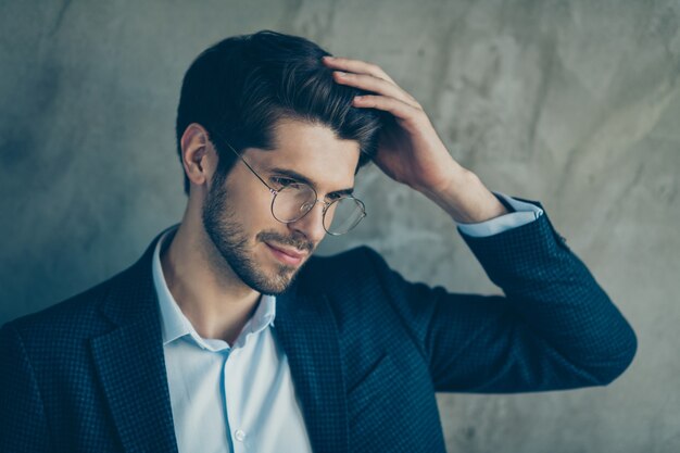 Homme d'affaires à la mode posant contre le mur gris