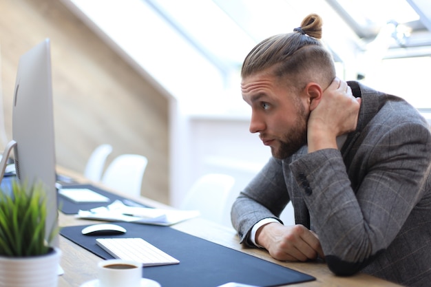 Homme d'affaires moderne pensant à quelque chose alors qu'il était assis au bureau.