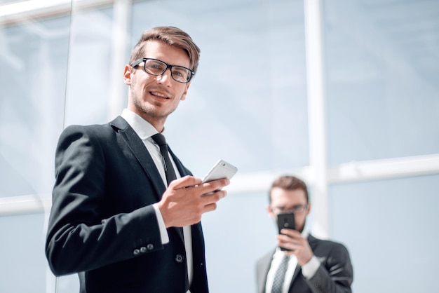 Homme d'affaires moderne avec un smartphone sur officephoto de fond avec espace de copie