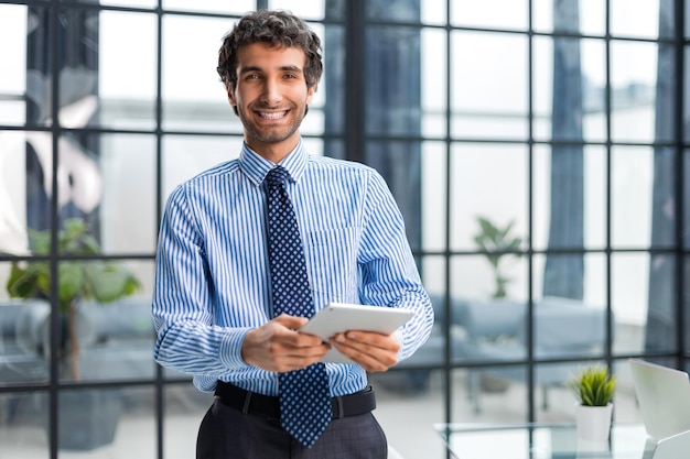 Homme d'affaires moderne utilisant une tablette numérique alors qu'il se tient au bureau