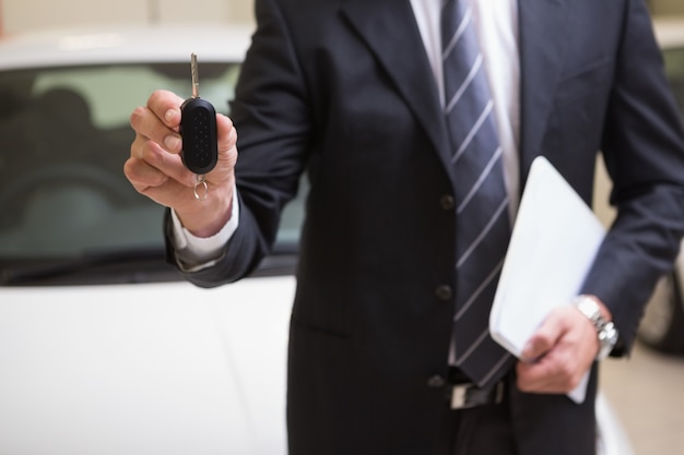 Homme d&#39;affaires montrant une clé de voiture tout en maintenant le presse-papiers