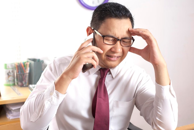 Un homme d'affaires montre une expression triste et choquée en recevant de mauvaises nouvelles au téléphone