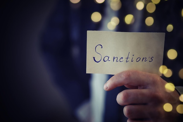 L'homme d'affaires montre la note de papier avec une inscription des sanctions
