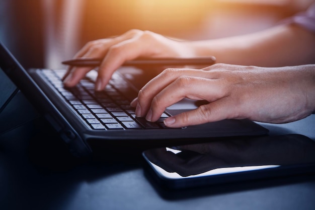 Homme d'affaires multitâche travaillant au bureau Il utilise le pavé tactile tout en lisant un e-mail sur un ordinateur portable et en prenant des notes sur le papier