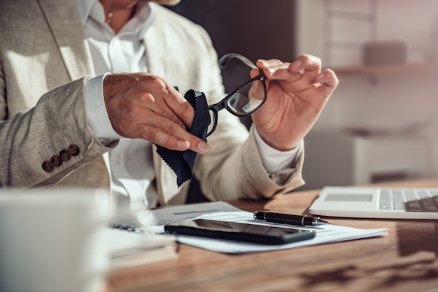 Homme d'affaires nettoyant ses lunettes de vue dans son bureau