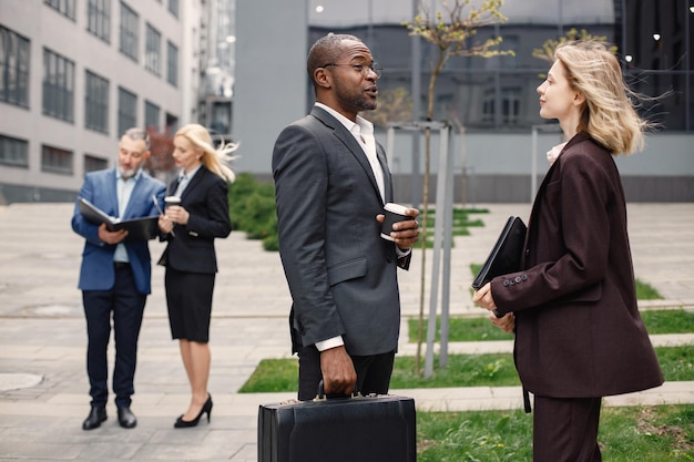 Homme d'affaires noir debout et parler avec une femme caucasienne devant un bureau moderne