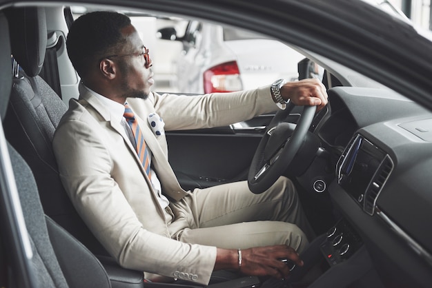 Homme d'affaires noir élégant assis au volant d'une nouvelle voiture de luxe. Riche homme afro-américain