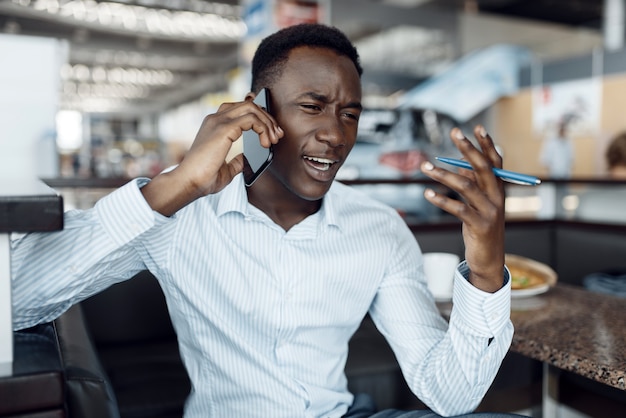 Homme D'affaires Noir Parlant Par Téléphone, Salle D'exposition De Voiture. Homme D'affaires Prospère Au Salon De L'automobile, Homme Noir En Tenue De Soirée