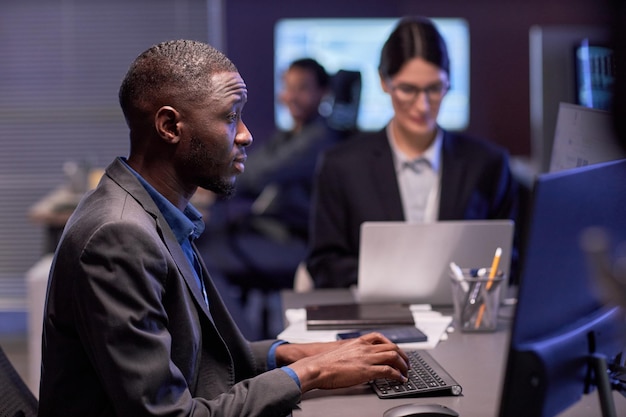 Homme d'affaires noir sérieux utilisant un ordinateur portable sur le lieu de travail dans un bureau informatique