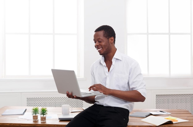 Un homme d'affaires noir travaille avec un ordinateur portable dans un bureau blanc moderne. espace de copie