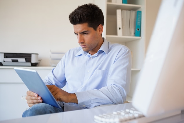 Homme d&#39;affaires occasionnel à l&#39;aide de sa tablette à son bureau