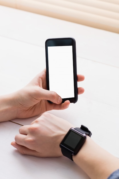 Homme d&#39;affaires occasionnel à l&#39;aide de téléphone et montre intelligente à son bureau