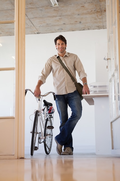 Homme d&#39;affaires occasionnel, debout avec son vélo, souriant à la caméra