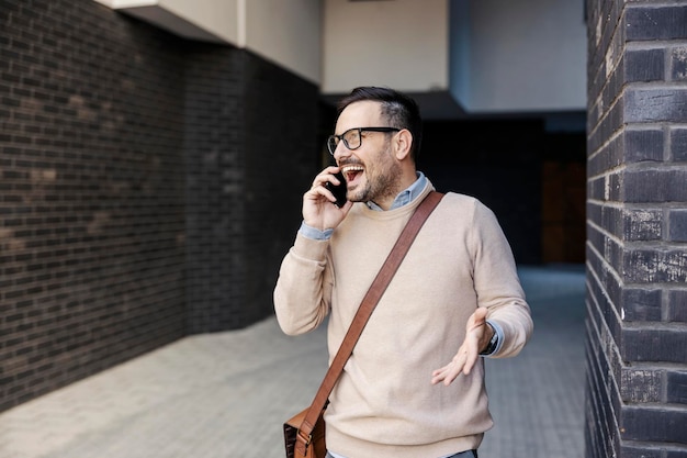 Un homme d'affaires occasionnel heureux parlant au téléphone dehors