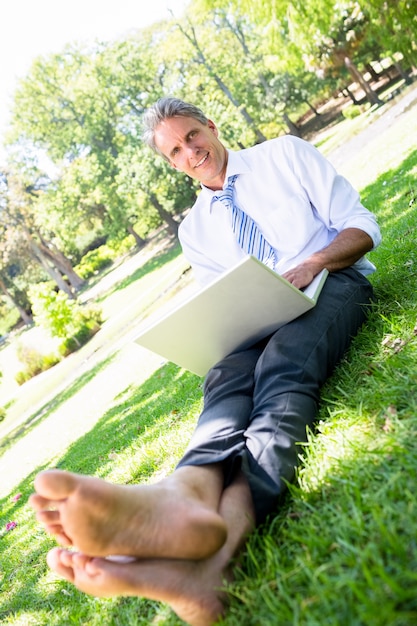Homme d&#39;affaires avec ordinateur portable assis sur un parc
