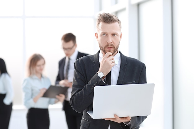 homme d'affaires avec ordinateur portable sur le fond du hall du bureau. les gens et la technologie