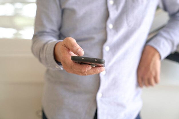 Homme d'affaires parcourant ou surfant sur son téléphone portable Clsoeup