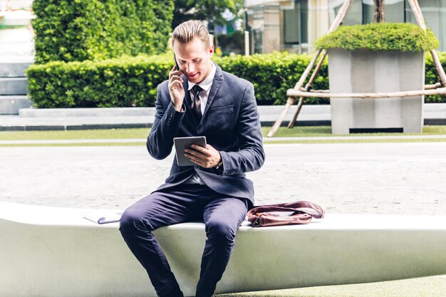 Photo homme d'affaires parlant au téléphone portable tout en regardant une tablette numérique