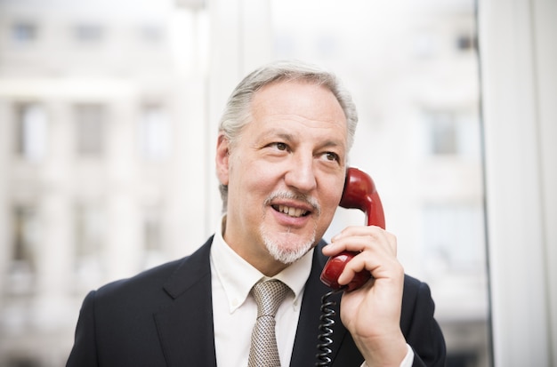 Homme d&#39;affaires parlant sur un téléphone vintage dans son bureau