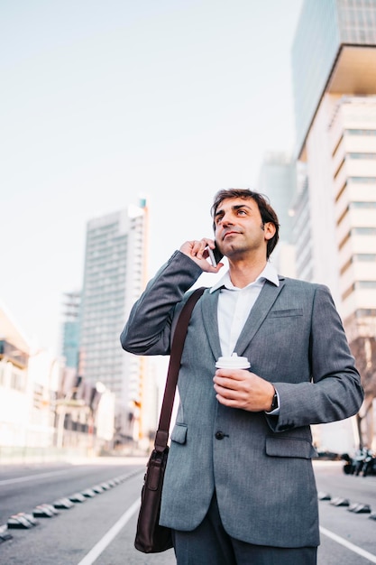 Un homme d'affaires parle au téléphone alors qu'il se tient sur la route.