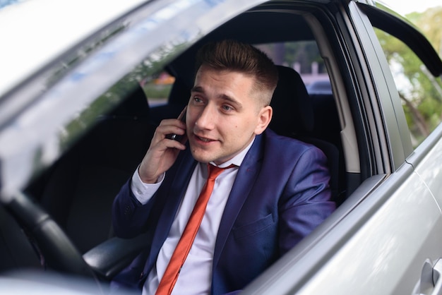 Un homme d'affaires parle au téléphone dans une voiture.