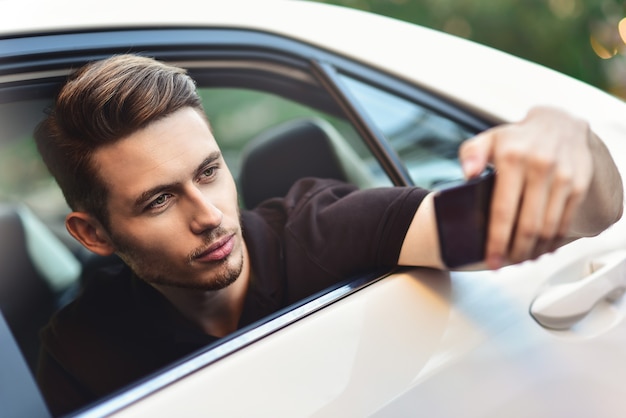 Un homme d'affaires passager utilise un smartphone sur le siège arrière de la voiture.