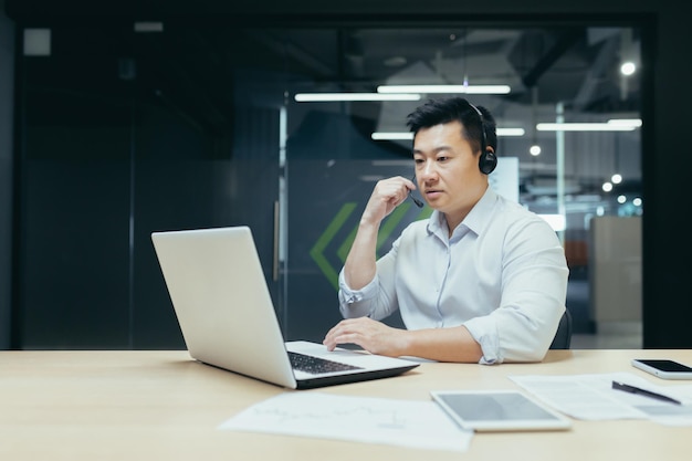 Homme d'affaires de patron employé asiatique prospère travaillant avec un ordinateur portable à l'aide d'un casque pour l'homme d'appel vidéo à