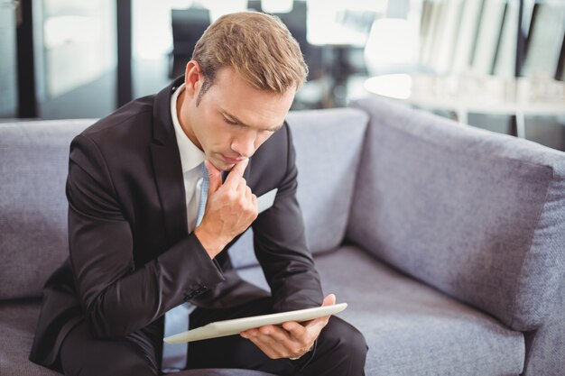 Homme d'affaires pensif regardant une tablette numérique