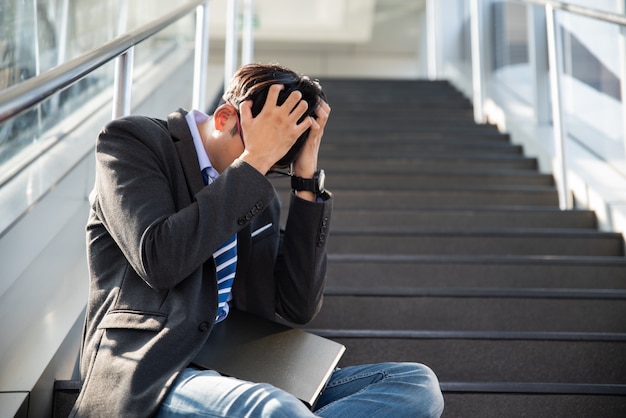 Homme d'affaires perdu dans la dépression pleurer assis dans les escaliers. A souligné le concept de chômage.