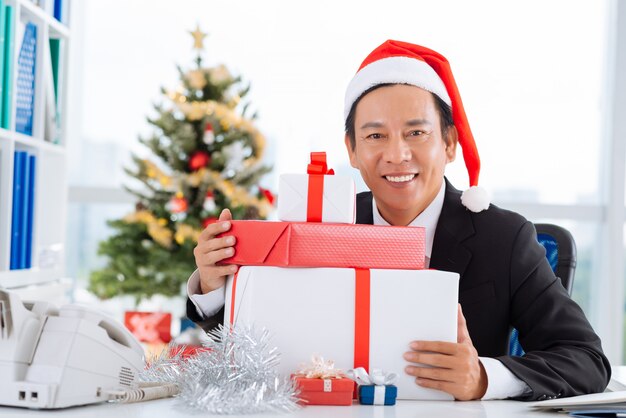 Homme d&#39;affaires avec une pile de boîtes-cadeaux